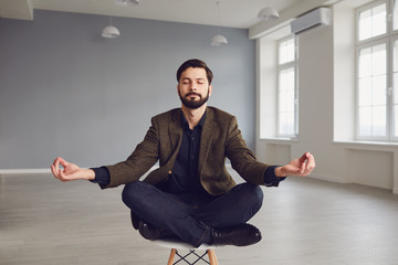 Calm meditative bearded businessman relaxes sitting on a chair in the office.
