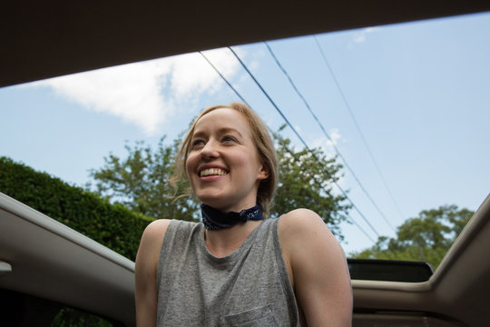 young 20s caucasian millennial woman out of sunroof of car