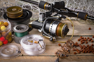 Fishing rods and spinnings in the composition with accessories for fishing on the old background on the table