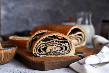 Rosy roll with poppy seeds and milk on a concrete background.