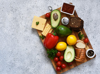 Different vegetables and products on the board on a concrete background.