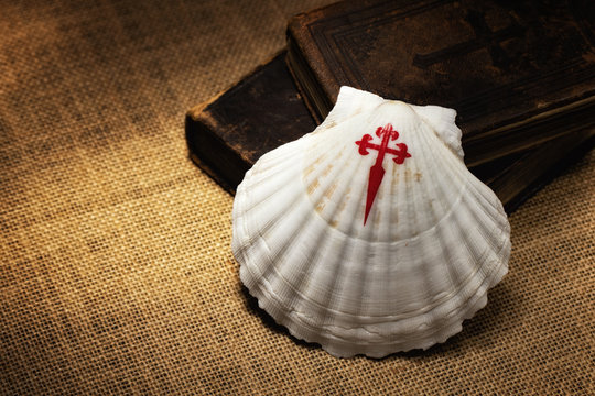 Symbol of the pilgrimage journey to Santiago de Compostela. Seashell and old books on the table. Camino de Santiago in Spain. Copy space.
