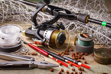 Fishing rods and spinnings in the composition with accessories for fishing on the old background on the table