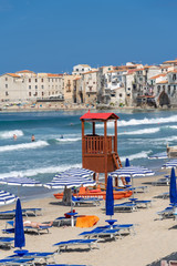 Cefalu village and people enjoying beach holiday on Mediterranean sea on the island coast of Sicily...