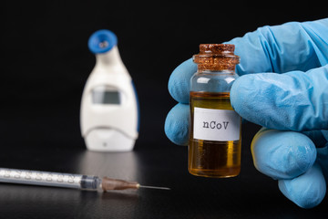 Glass vial, syringe with needle and thermometer on the table. A serious flu virus in the laboratory.
