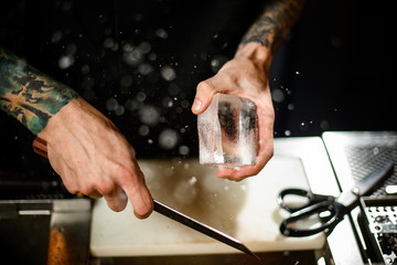 Close-up of bartender crushing ice with sharp knife