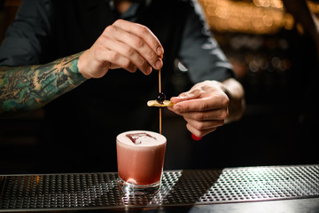 Close-up of bartender adding olive to alcohol drink
