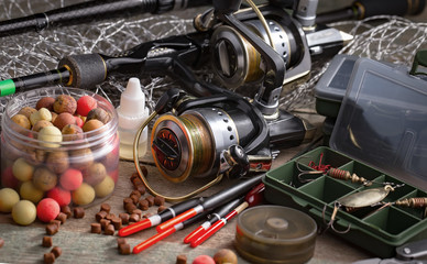 Fishing rods and spinnings in the composition with accessories for fishing on the old background on the table