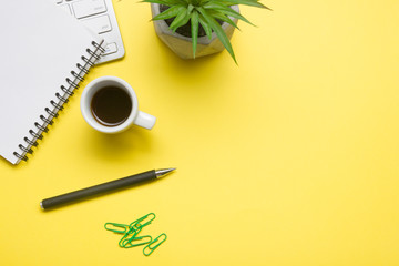 Yellow desk office with laptop, smartphone and other work supplies with cup of coffee. Top view...