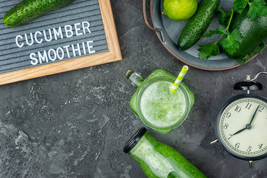 On a black background, cucumber smoothie and ingredients. Flat lay with copy space. Blackboard with the words Cucumber Smoothies. Healthy breakfast of green vegetables, vegetarianism.