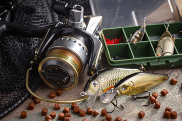 Fishing rods and spinnings in the composition with accessories for fishing on the old background on the table