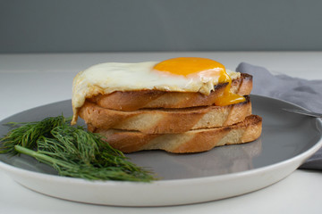 Breakfast of fried egg and croutons, dill. Gray background. Horizontal orientation.