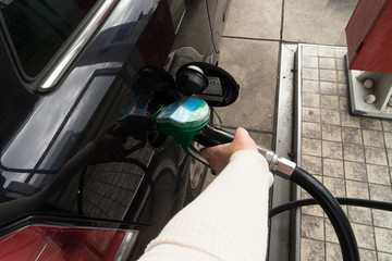 Female hand fill gasoline in a car with gas pump nozzle