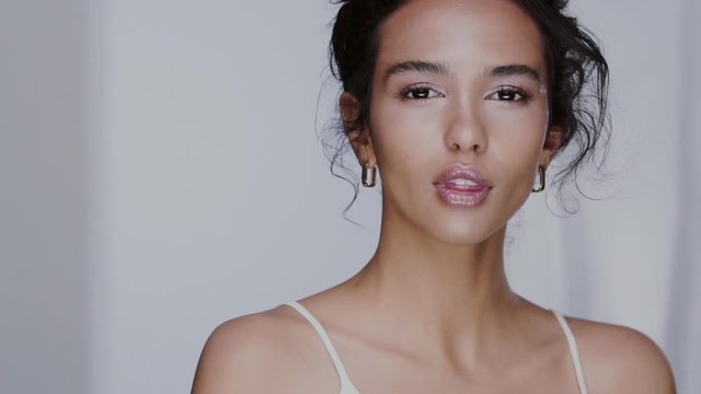 charming female model putting cosmetic on her cheek and wind blows her black hair
