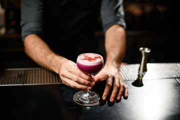 Delicious looking alcohol cocktail in bartender's hands