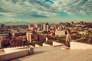 Yerevan cityscape from complex cascade. Touristic architecture landmark. City tour. Tourist woman enjoy travel to Armenia. Tourism concept. Sunny autumn day. Mountain Ararat on background. Copyspace