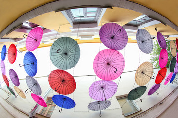 colorful decorative umbrellas hang between the buildings as protection from the sun and rain