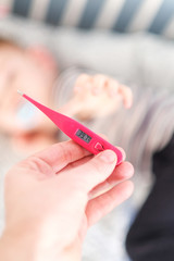 Little baby boy has got a flu. Hand holding a thermometer.