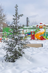 A christmas tree on a city children's playground. A winter are in the city. Fresh snow was fell.