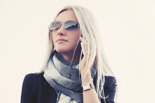 Blond fashion business woman in sunglasses using cell phone