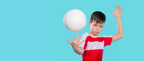 Caucasian boy serving the ball in volleyball isolated on a blue background