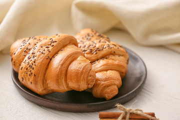 Plate with tasty croissants on white table