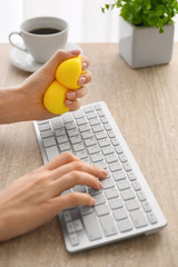 Woman squeezing stress ball while working in office