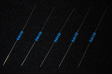 small electronic resistors making parallel lines on a black fabric background