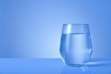 Glass of fresh water on color background