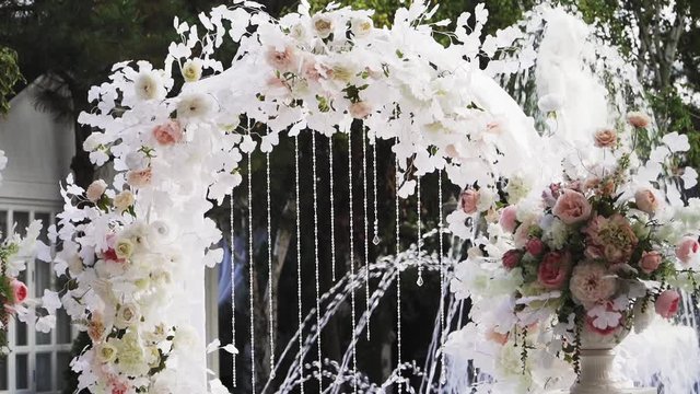 Beautiful wedding arch on the marriage of the colors of roses. On the background of the fountain. slow motion