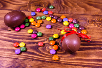 Chocolate easter eggs and multicolored candies on wooden table