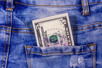 American five dollar banknote in a pocket of blue jeans