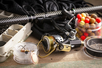 Fishing rods and spinnings in the composition with accessories for fishing on the old background on the table