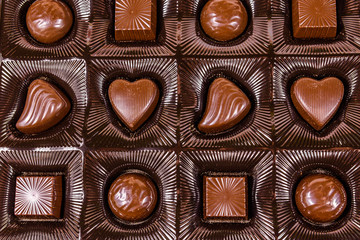 Heap of chocolate candies in a brown box. Top view