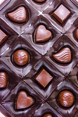Heap of chocolate candies in a brown box. Top view