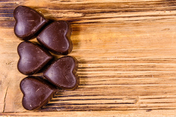 Heap of heart shaped chocolate candies on a wooden table. Top view. Valentine day concept