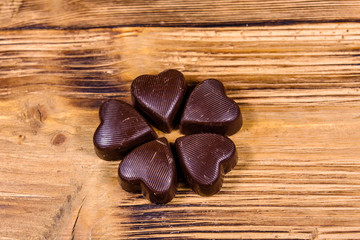 Heap of heart shaped chocolate candies on a wooden table. Valentine day concept