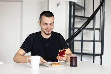 The guy has breakfast with toast with jam.