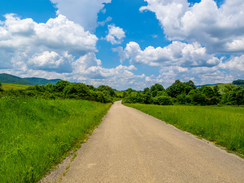 Empty asphalt country road vanishes to the right. Amazing June Bulgarian Fore-Balkan rural landscape