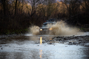 Fototapeta premium 4x4 travel trekking. Scene of wather splash in off-road racing. Safari suv. Getting off the beaten path. Racer at terrain racing car competition. Off road sport truck between mountains landscape.