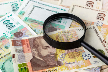 Magnifier on bulgarian lev banknotes. Check the authenticity of money. Wealth, poverty and counterfeiting money concept.