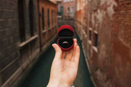 Woman holding red box with engagement ring front venetian canal. An offer of marriage in Venice, Italy. Film effect, author processing of photo.