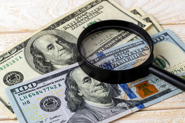 Magnifier on new and old dollar banknotes on a white wooden surface. Check the authenticity of money. Wealth, poverty and counterfeiting money concept.