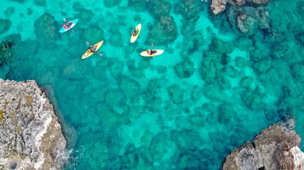 Poster view of a drone from a drone people are kayaking in the sea near the mountains in a cave with turquoise water on the island of Cyprus Ayia Napa © Sheviakova