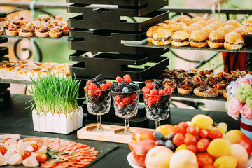 Glasses with berries on a festive table decorated with grass.Party bar. A table with food at a children's birthday. Outdoor party.
