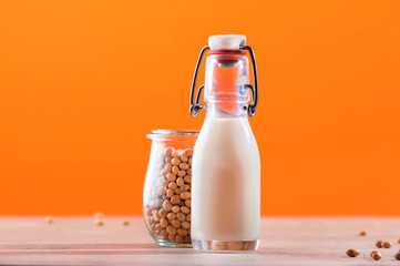 Soy milk and soy bean on orange background. Non-dairy milk concept. Vegan Drink. Copy space