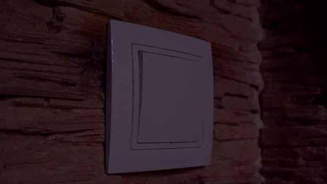 The light is off - the male hand turns off or turns on the button on the wall, front view