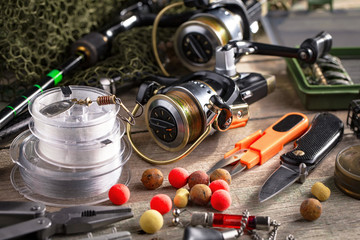 Fishing rods and spinnings in the composition with accessories for fishing on the old background on the table