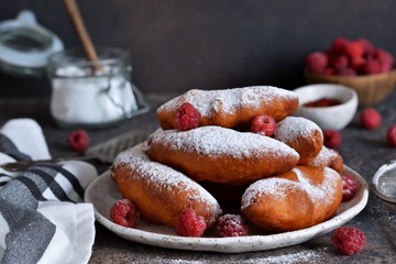 Fried donuts with filling. Patties with berries and powdered sugar on a plate on a concrete background.