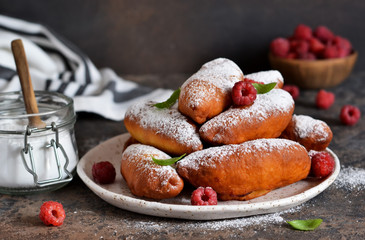 Fried donuts with filling. Patties with berries and powdered sugar on a plate on a concrete background.
